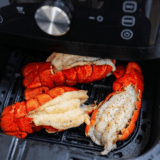 Air fryer lobster tails brushed with lemon garlic butter on a serving plate