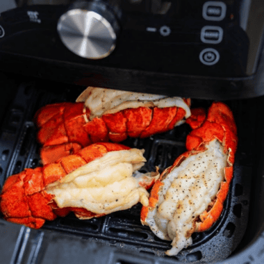 Air fryer lobster tails brushed with lemon garlic butter on a serving plate