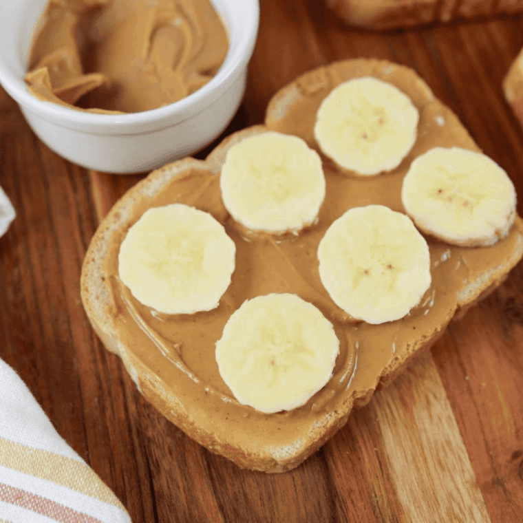 Peanut butter-covered bread topped with thin banana slices, drizzled with honey and sprinkled with cinnamon.