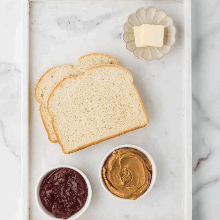 ingredients needed for air fryer peanut butter and jelly sandwich on kitchen table.