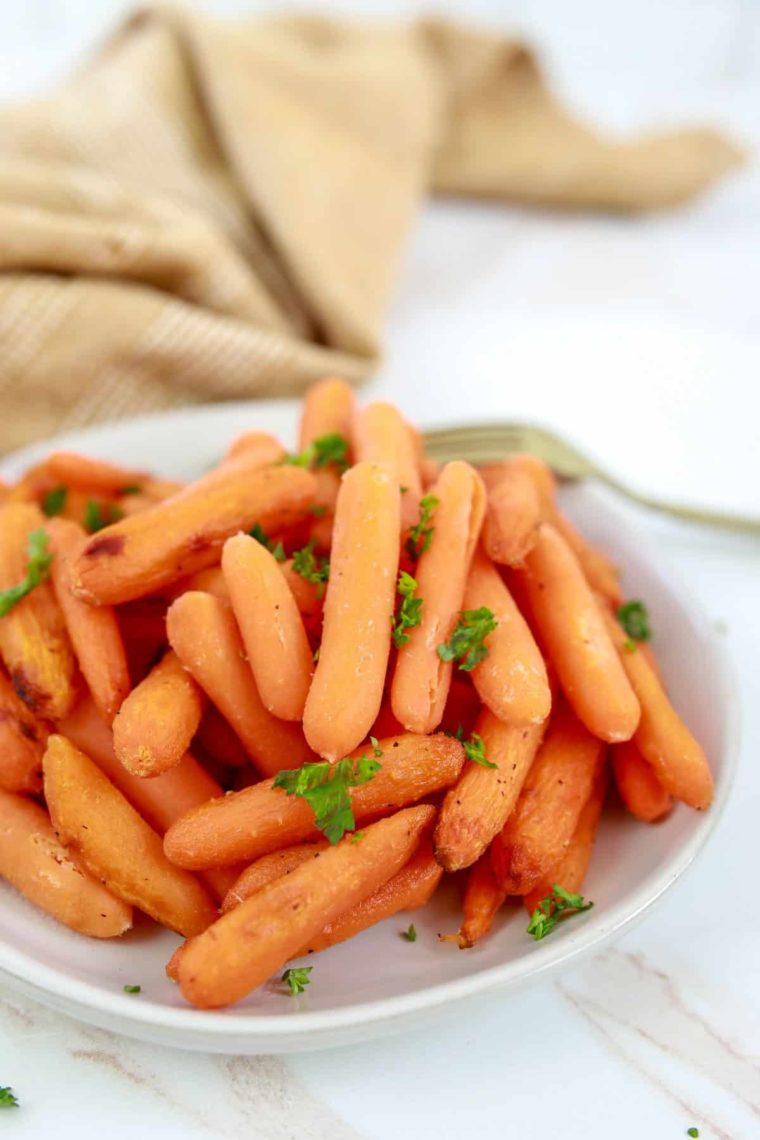 a plate of honey roasted carrots from air fryer with herbs on top