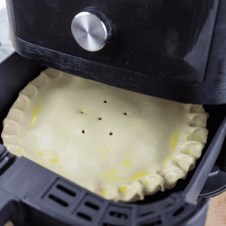 Removing the cherry pie from the air fryer and letting it cool slightly before slicing and serving, with options to add vanilla ice cream or whipped cream.