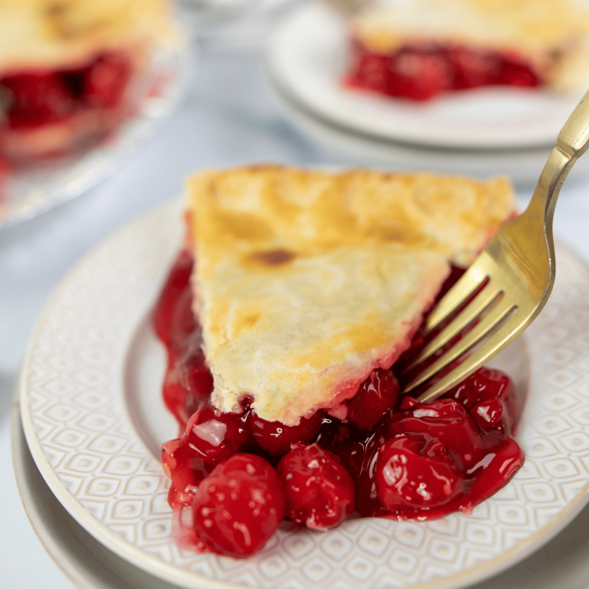 Golden, flaky whole cherry pie made in the air fryer, topped with a lattice crust and filled with sweet cherry filling.