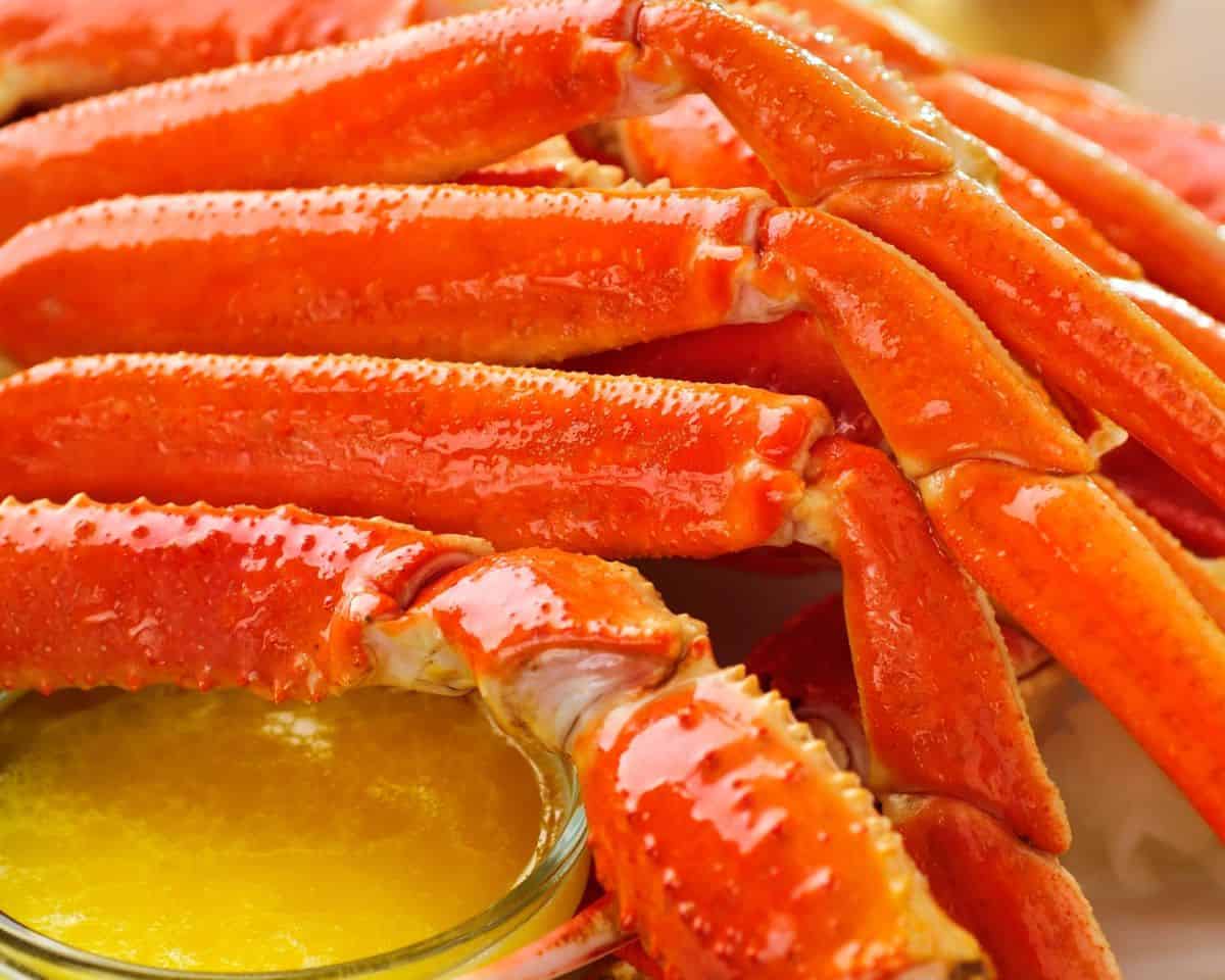 Up close shot of crab legs with melted butter tucked under them. 