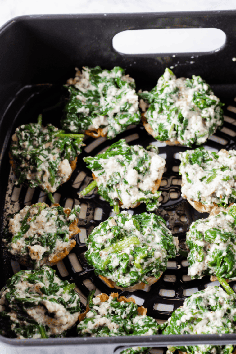 Air fryer basket with filled phyllo cups cooking until golden.