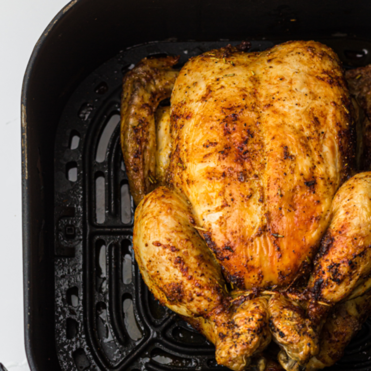 Close-up of crispy skin on air fryer whole chicken with lemon and thyme seasoning.