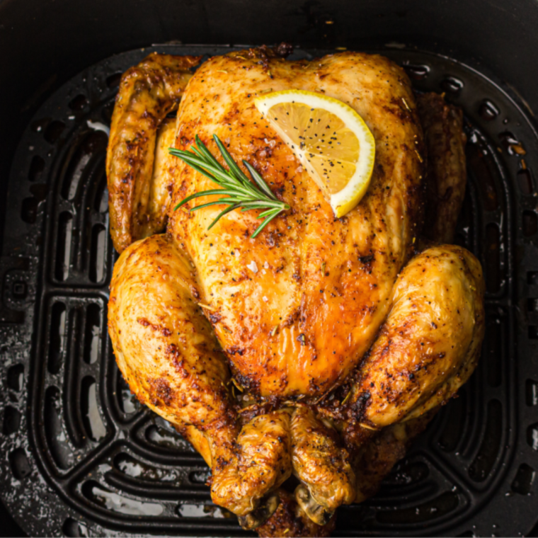 Image of a golden-brown whole chicken seasoned with lemon and thyme, resting on a platter garnished with fresh herbs and lemon slices.