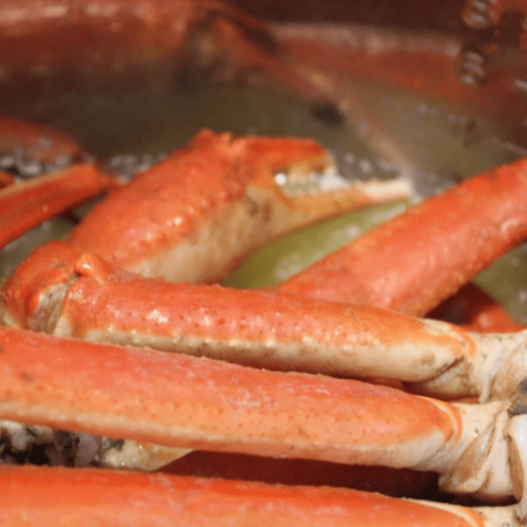 A plate of tender Instant Pot crab legs garnished with parsley and lemon wedges.