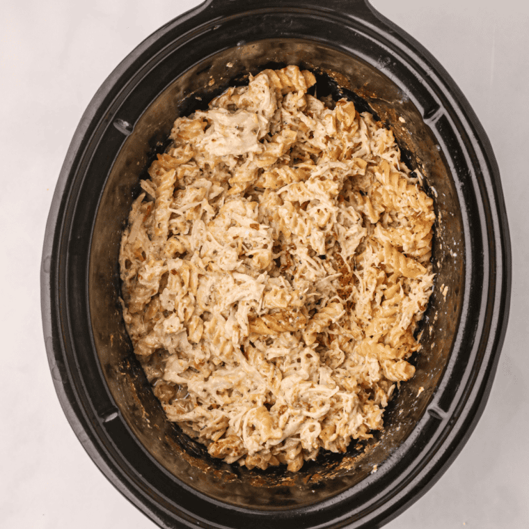 Seasoned chicken cooking in a slow cooker until tender for slow cooker chicken quesadillas