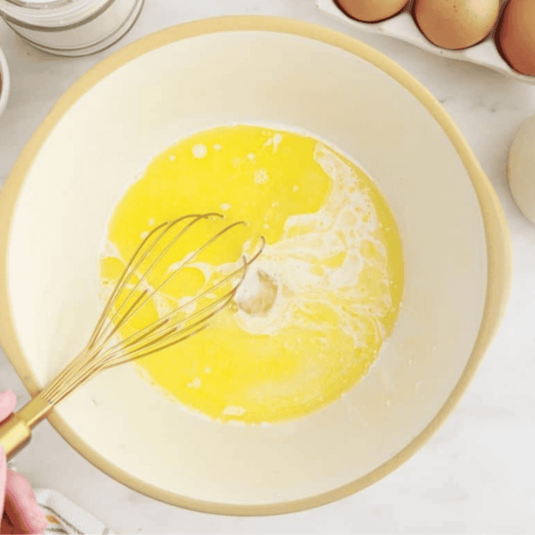 Mixing honey, sugar, eggs, cream, and melted butter in a large bowl for a cornbread casserole.