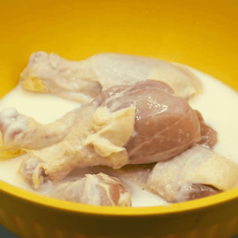 Raw chicken soaking in buttermilk in a large bowl for air fryer Kentucky Kernel fried chicken
