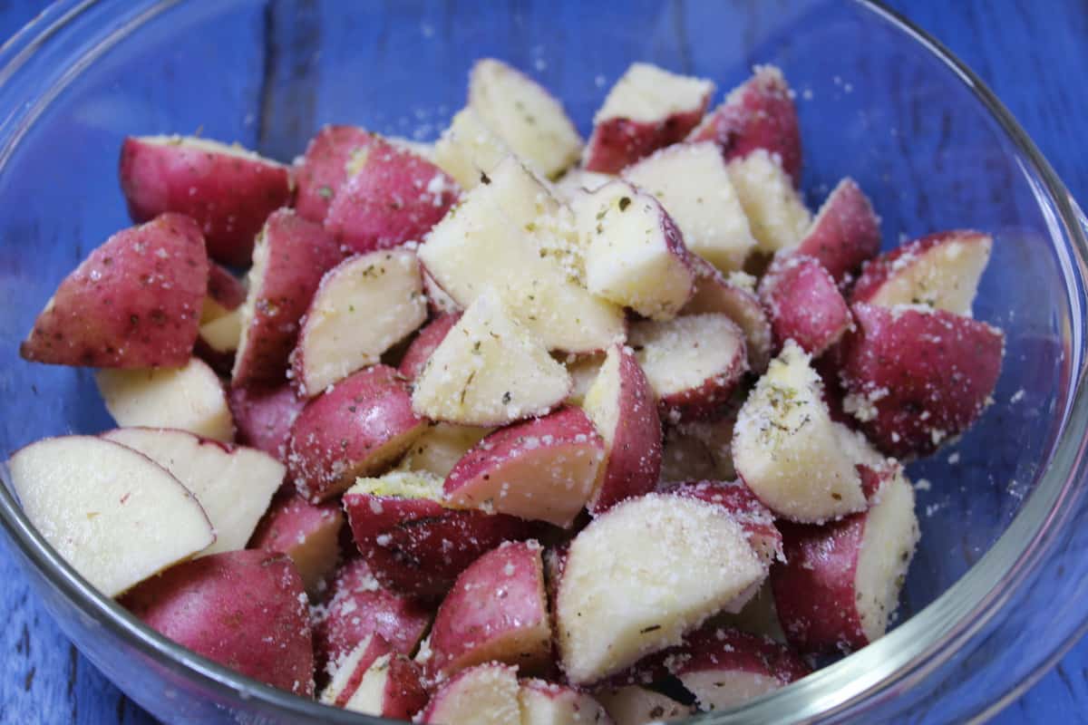 seasoning red potatoes in a glass bowl 