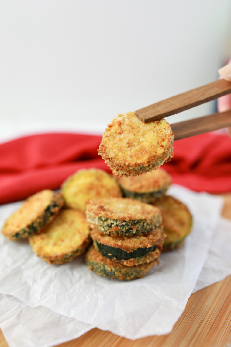 Crispy air fryer zucchini zircles coated in breadcrumbs and cooked until golden brown served with dipping sauce on a plate