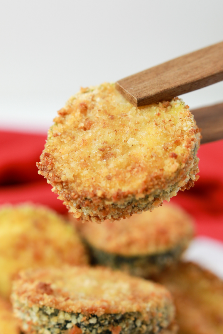 Golden crispy air fryer zucchini zircles coated in breadcrumbs served with dipping sauce on a plate ready to eat