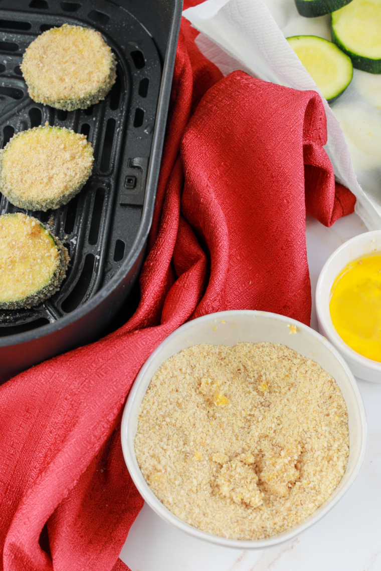 Dipping zucchini slices in egg and coating with breadcrumbs for crispy crust