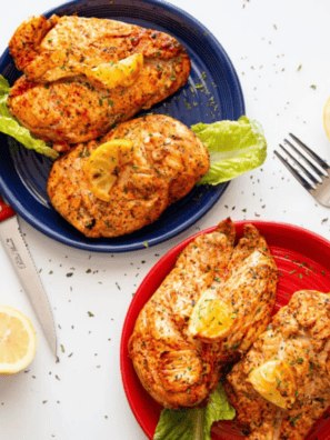 Air fryer lemon pepper chicken breast sliced on a white plate with fresh lemon wedges and parsley