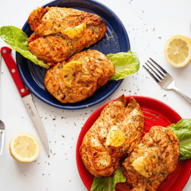 Air fryer lemon pepper chicken breast sliced on a white plate with fresh lemon wedges and parsley