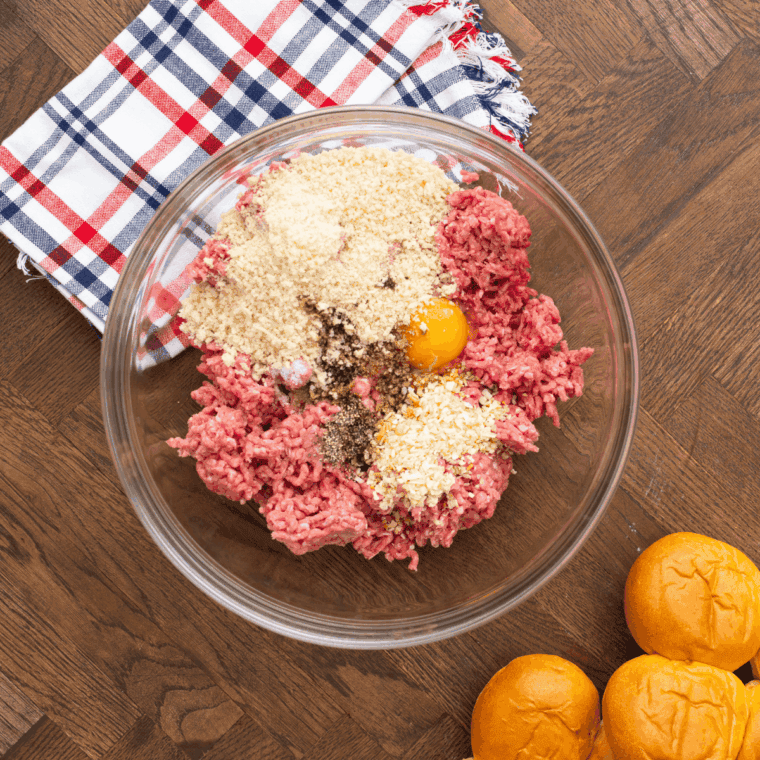 Mixing ground beef with onion, seasonings, egg, breadcrumbs, and Worcestershire sauce in a large bowl to make tender burger patties.