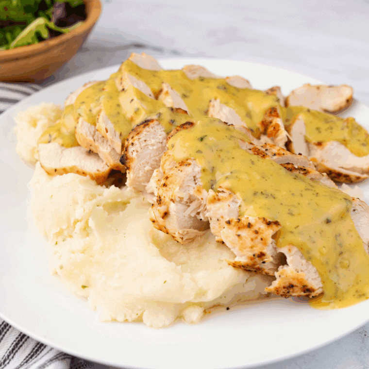 Air-fried chicken topped with creamy Dijon mushroom sauce and fresh parsley on a plate.