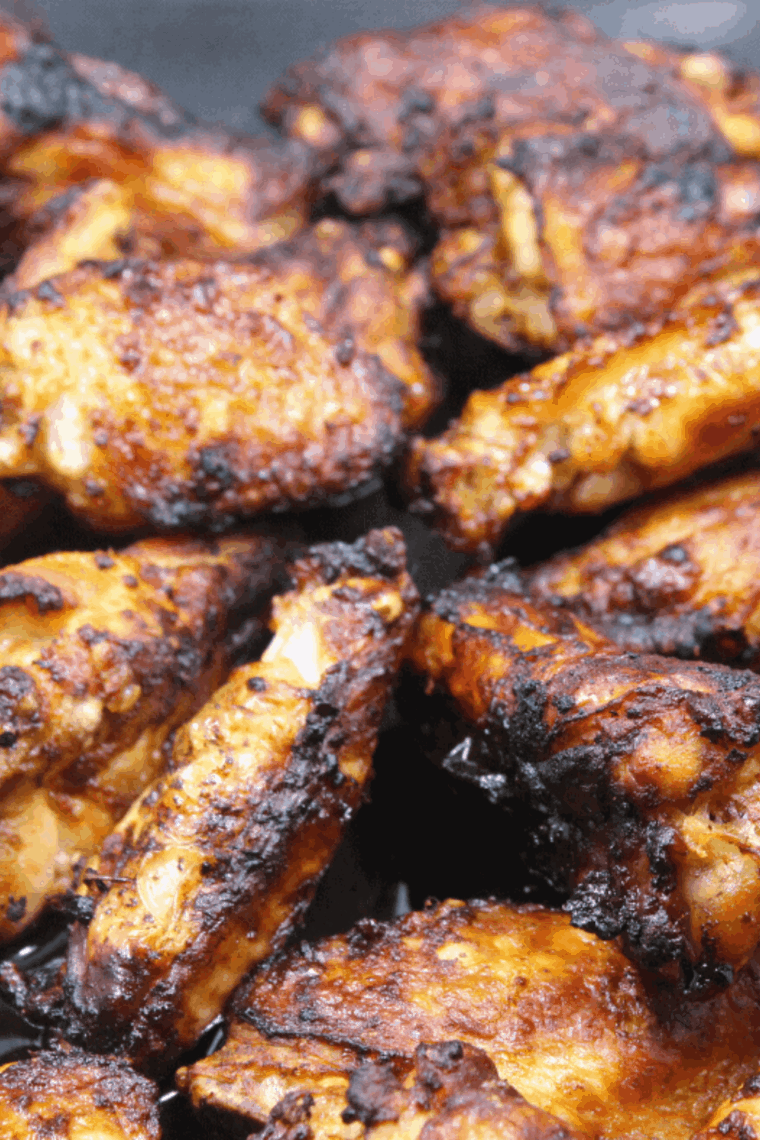 Crispy air fryer chicken wings glazed with lemon dijon sauce, served on a white plate with fresh herbs.
