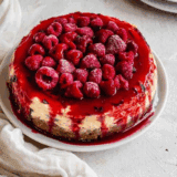 Slice of Cheesecake Factory Lemon Raspberry Cream Cheesecake with raspberry swirls and lemon topping.