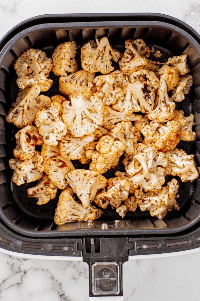 Cauliflower tossed in olive oil, garlic powder, onion powder, smoked paprika, salt, and black pepper in a large bowl.