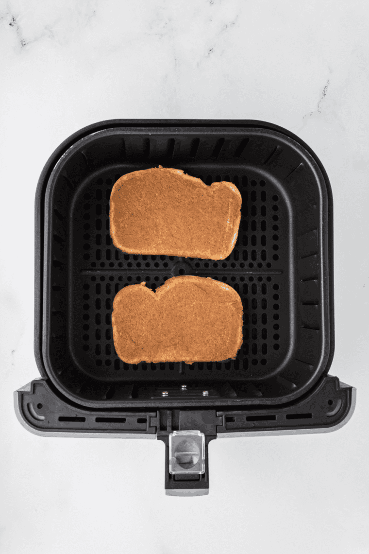 Placing prepared bread slices in the air fryer basket to cook at 400°F for 2-5 minutes.