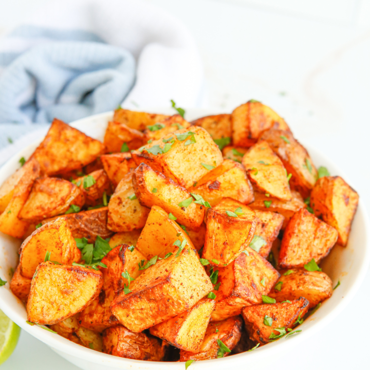 Crispy Air Fryer potatoes infused with lemon and rosemary served on a rustic wooden table.