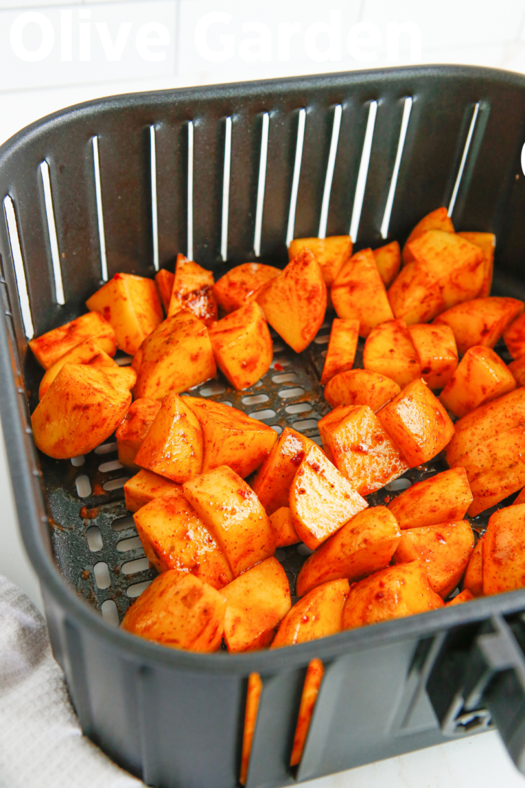 Placing seasoned potatoes in the air fryer basket for cooking.