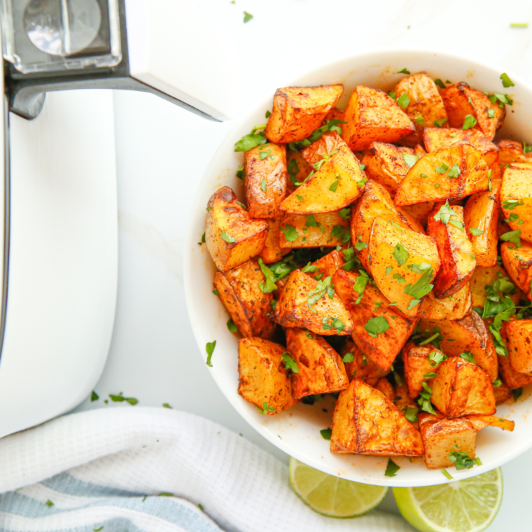 Deliciously golden Air Fryer Lemon and Rosemary Roasted Potatoes served on a white plate, garnished with fresh rosemary and lemon slices, showcasing a crispy exterior and fluffy interior.