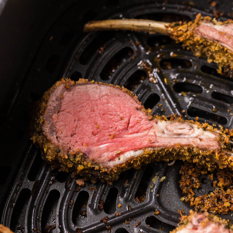 Close-up of herb-crusted rack of lamb sliced into chops inside the air fryer basket