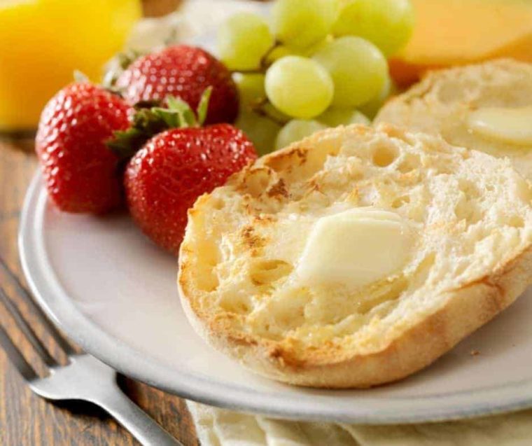 closeup: toasted english muffins from air fryer with butter on a plate with strawberries and grapes