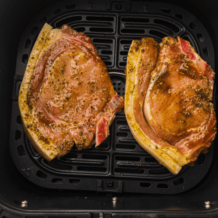 Cooking seasoned pork chops in the air fryer, flipping halfway, until fully cooked and golden brown.