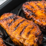 Air fryer blackened pork chops sliced to show juicy pink center and dark Cajun spice crust