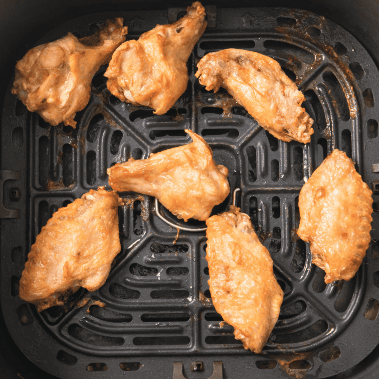 Frozen wings partially thawing in the air fryer at 400°F, with some wings being separated halfway through cooking using tongs.