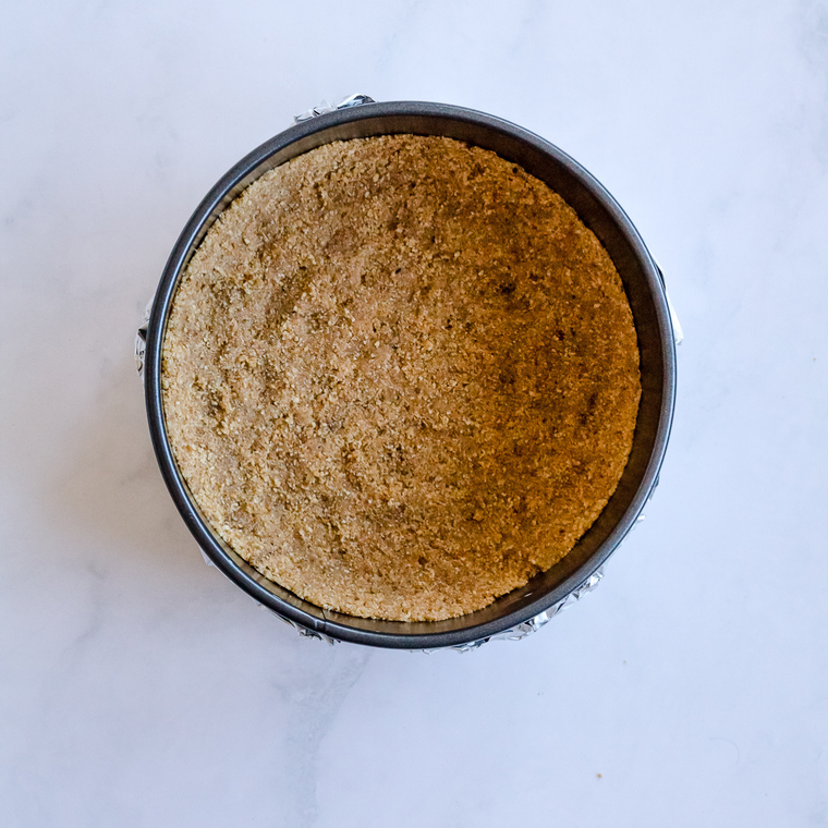 Graham cracker crumbs mixed with melted butter in a bowl for cheesecake crust