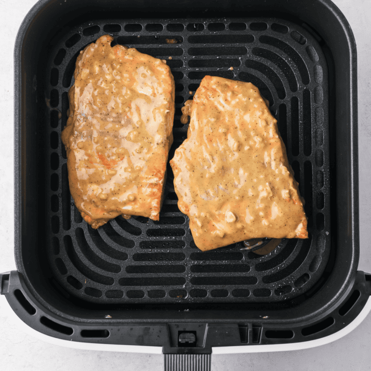 Air fryer honey mustard salmon cooking in the basket with a caramelized glaze.
