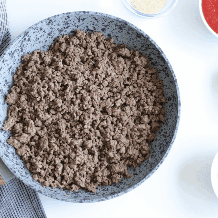 Mixing water, tomato paste, and sloppy joe seasoning into beef