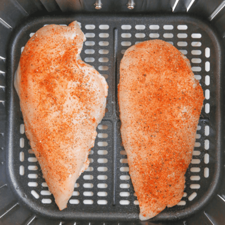 Chicken breasts being dipped in the breadcrumb mixture, ready to be baked or air fried.