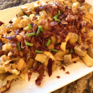 Plate of Air Fryer Cheesy Bacon Roasted Potatoes with crispy edges and melted cheese