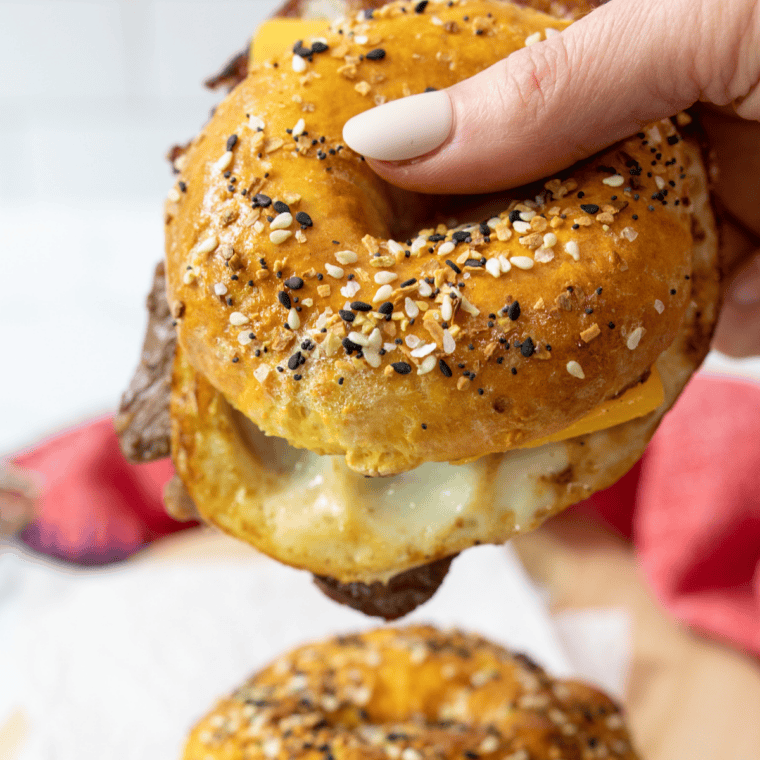Finished air fryer bagel breakfast sandwich with egg, sausage, and melted cheese served on a plate