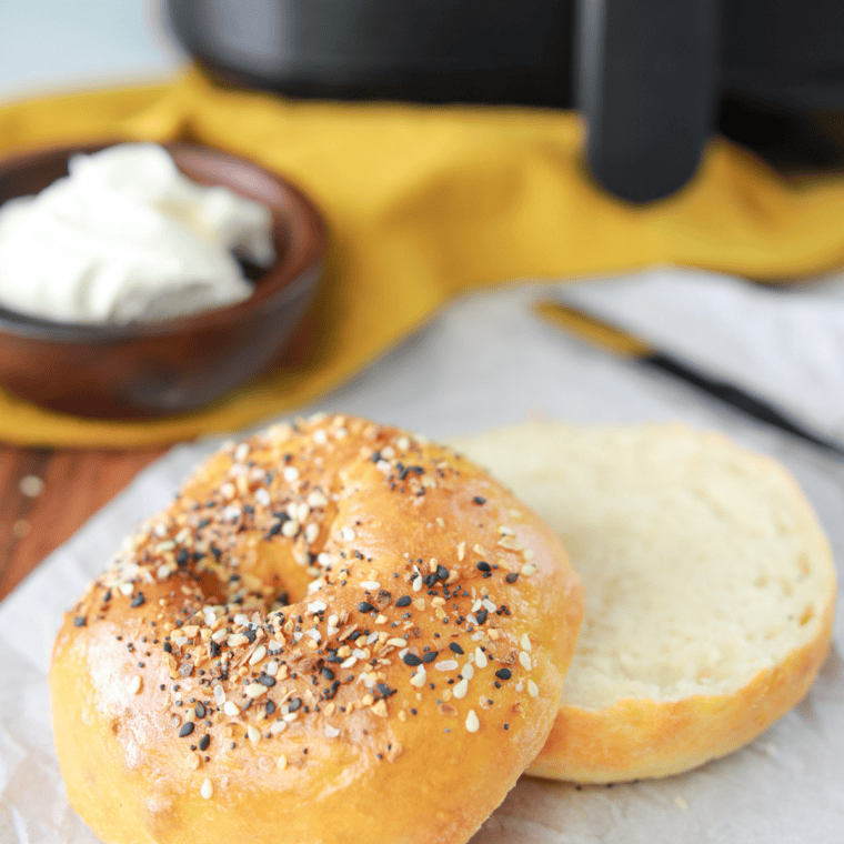 Halved homemade bagel and an egg in a ramekin placed in the air fryer basket at 330&deg;F
