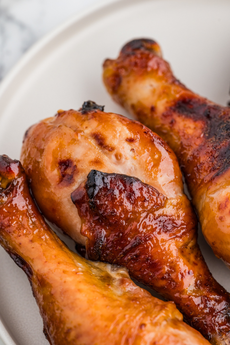 Golden-brown Air Fryer Honey Soy Chicken Drumsticks served on a plate with sesame seeds and green onions.