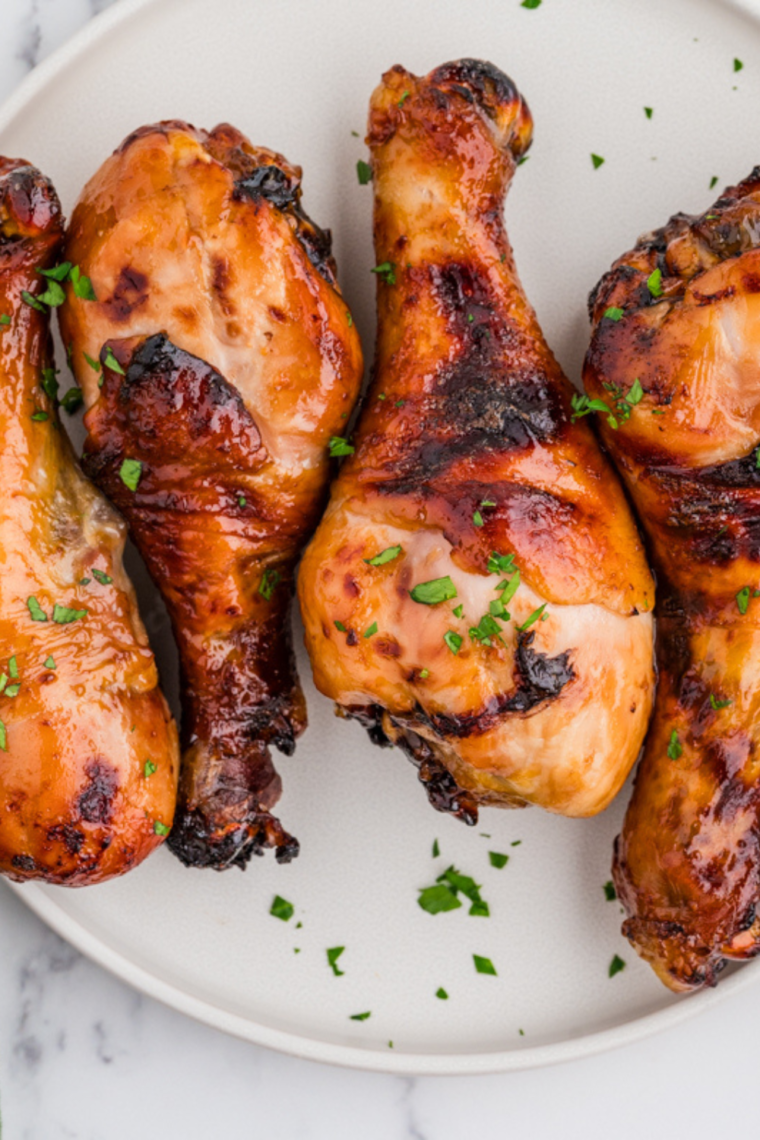 Crispy Air Fryer Honey Soy Chicken Drumsticks with a rich glaze, garnished with sesame seeds and green onions on a serving plate.