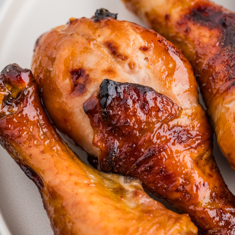 Crispy Air Fryer Honey Soy Chicken Drumsticks with a glossy glaze, served on a white plate with sesame seeds and green onions.