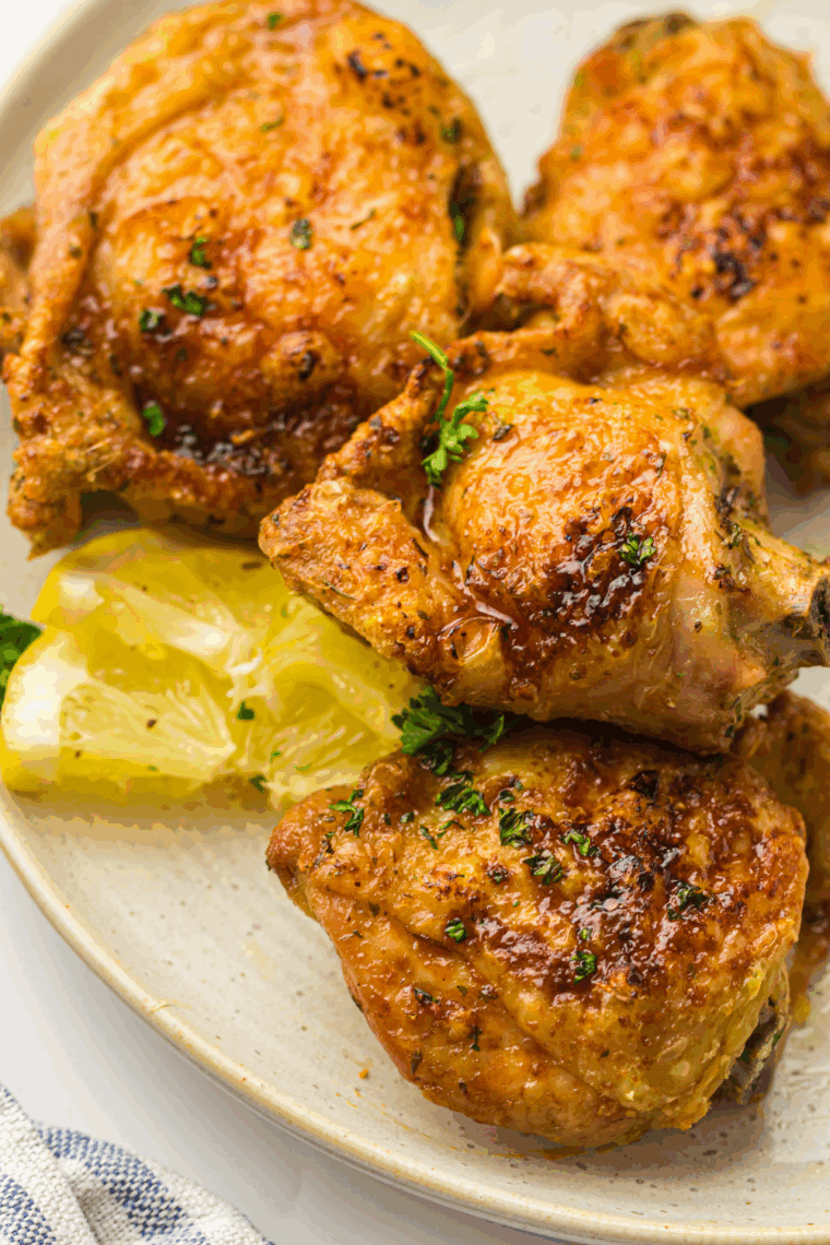 "Juicy air fryer lemon garlic chicken thighs with crispy skin and fresh lemon slices"