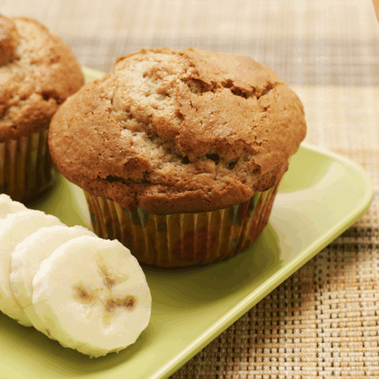 Plate of freshly baked Easy Banana Cardamom Muffins with golden tops, showing soft, fluffy texture and a warm banana aroma.