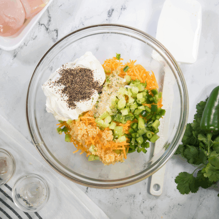 Mixing cream cheese, shredded cheddar, diced jalapeños, and bacon in a bowl for stuffed chicken filling.