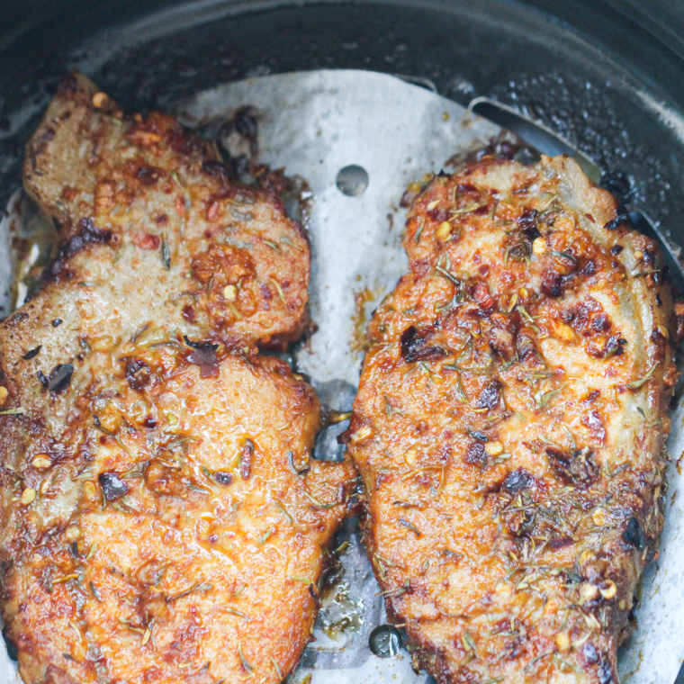 Cooked pork steaks resting on a cutting board before slicing