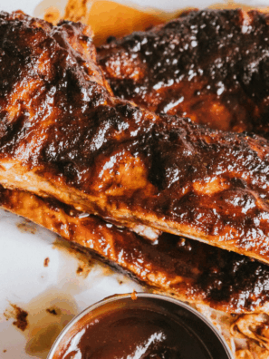 Plate of tender, saucy Chili’s Baby Back Ribs served with fries and coleslaw on a rustic wooden table.